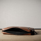 Brown leather bag with X detail and shoulder strap.