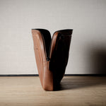 Brown leather bag with X detail and shoulder strap.