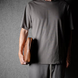 Brown leather bag with X detail and shoulder strap.