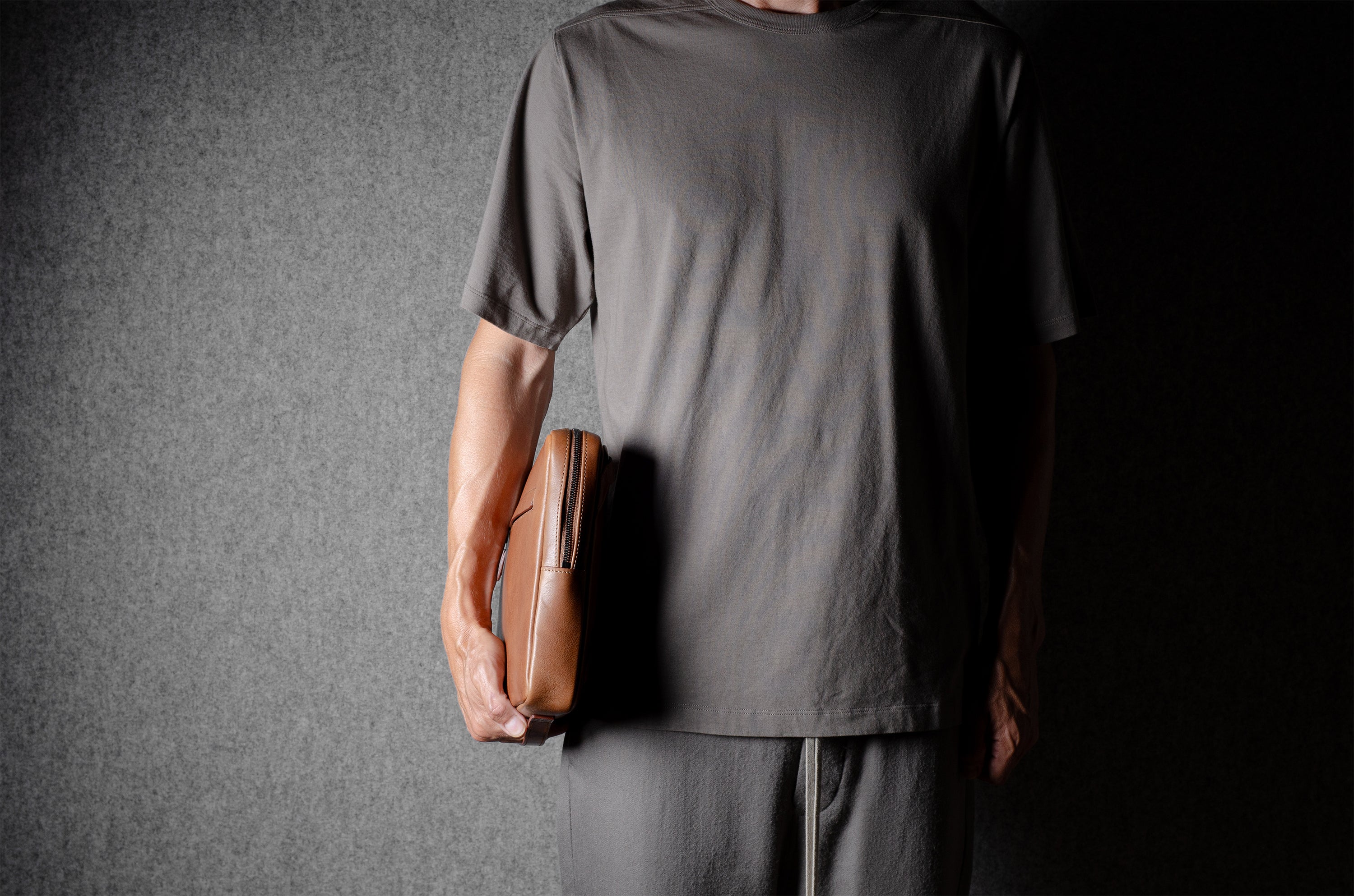 Brown leather bag with X detail and shoulder strap.