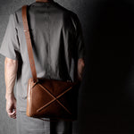 Brown leather bag with X detail and shoulder strap.