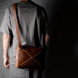 Brown leather bag with X detail and shoulder strap.