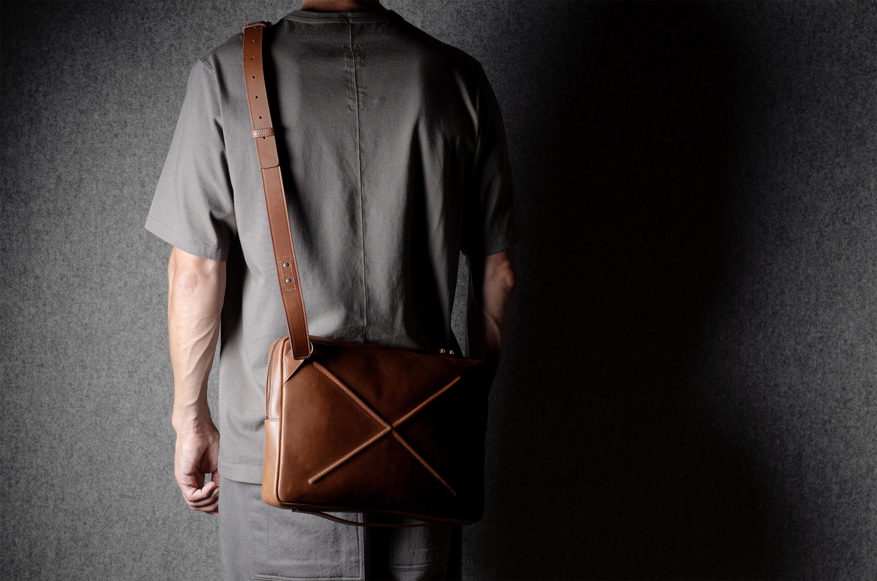 Brown leather bag with X detail and shoulder strap.