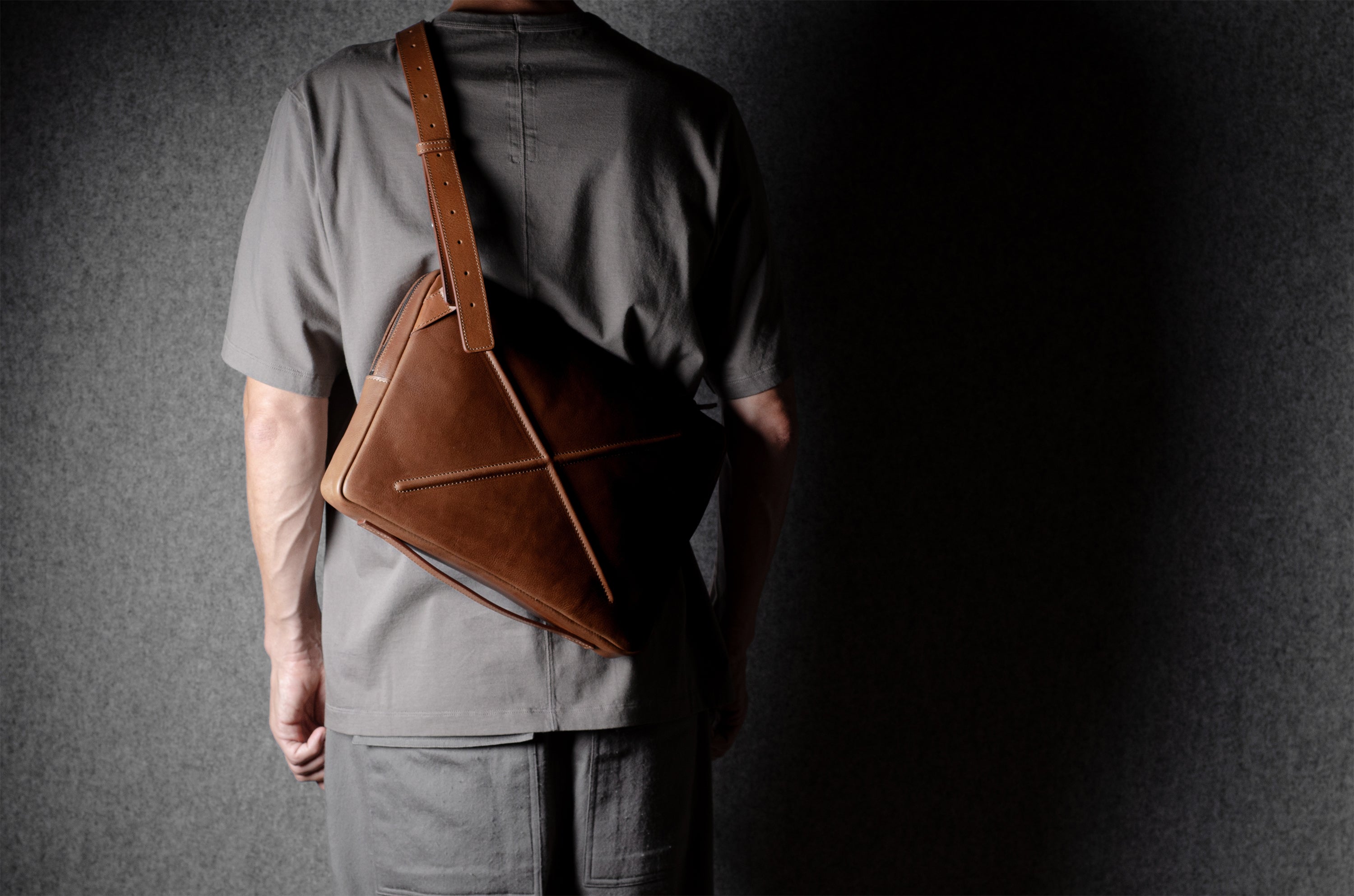 Brown leather bag with X detail and shoulder strap.