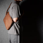 Brown leather bag with X detail and shoulder strap.