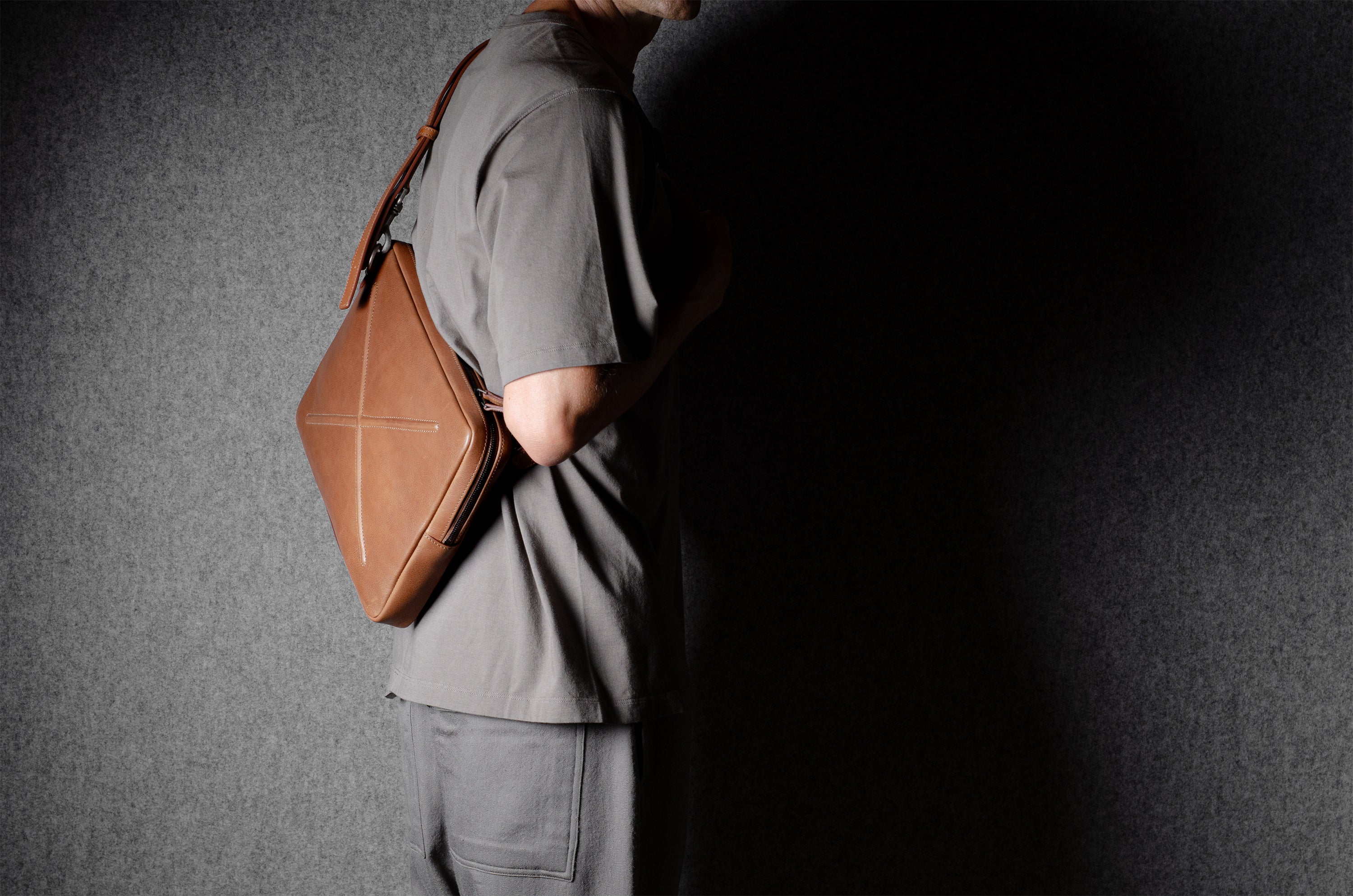 Brown leather bag with X detail and shoulder strap.