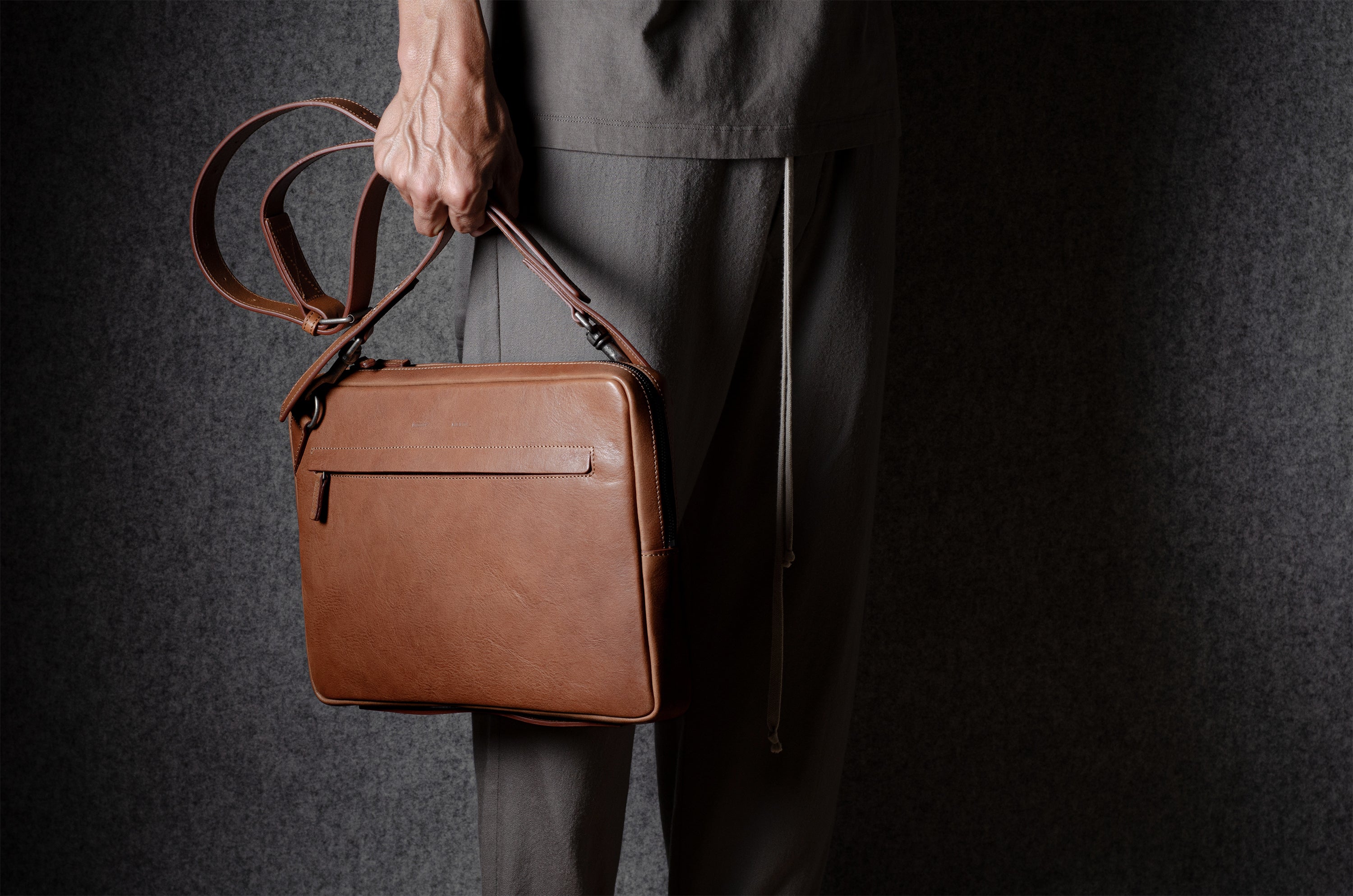 Brown leather bag with X detail and shoulder strap.