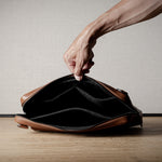 Brown leather bag with X detail and shoulder strap.