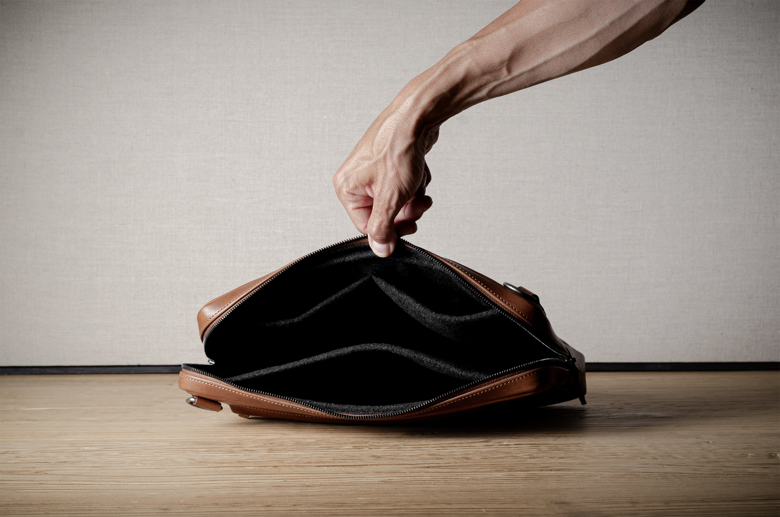Brown leather bag with X detail and shoulder strap.