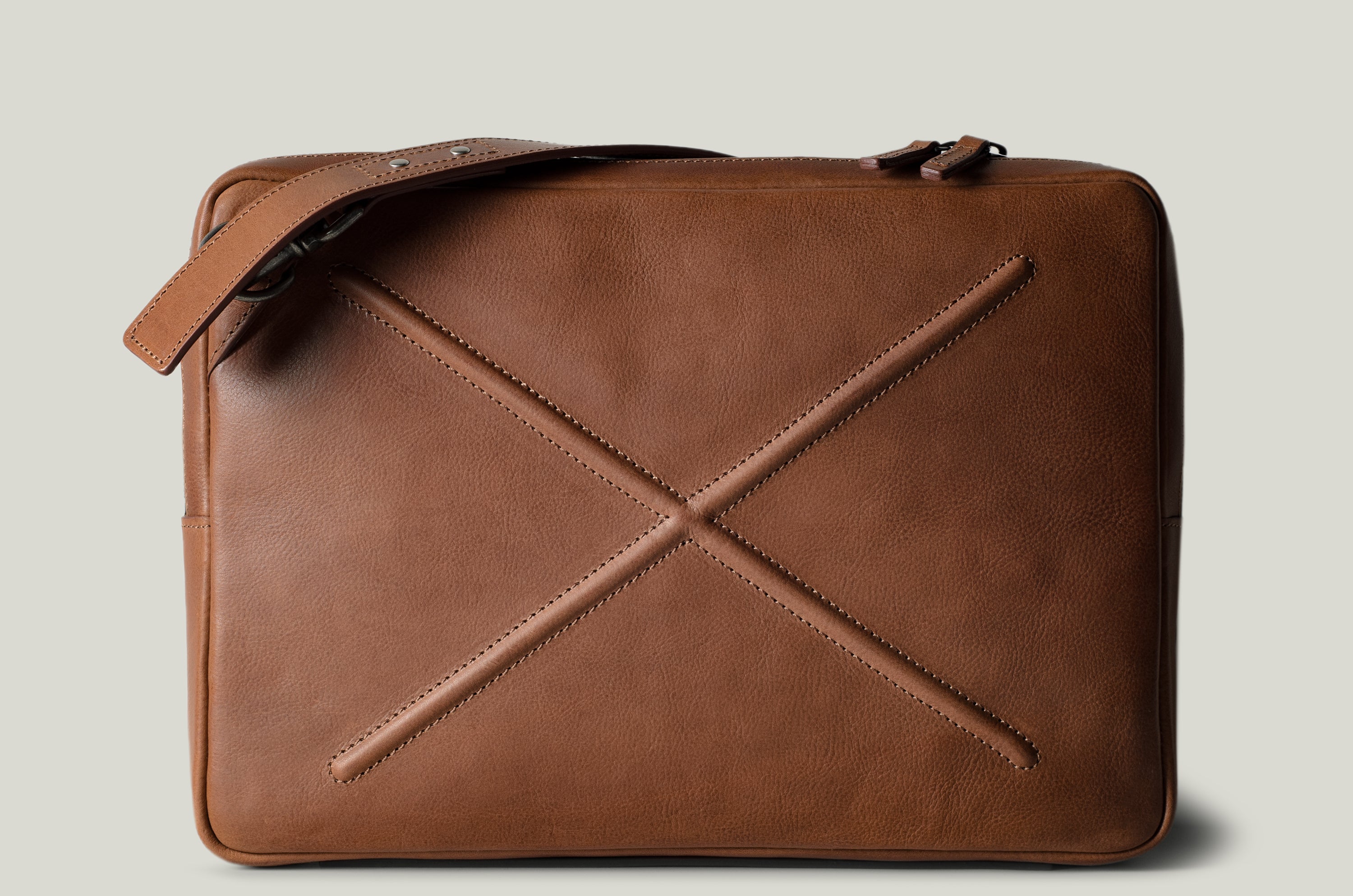 Brown leather bag with X detail and shoulder strap.