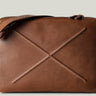 Brown leather bag with X detail and shoulder strap.