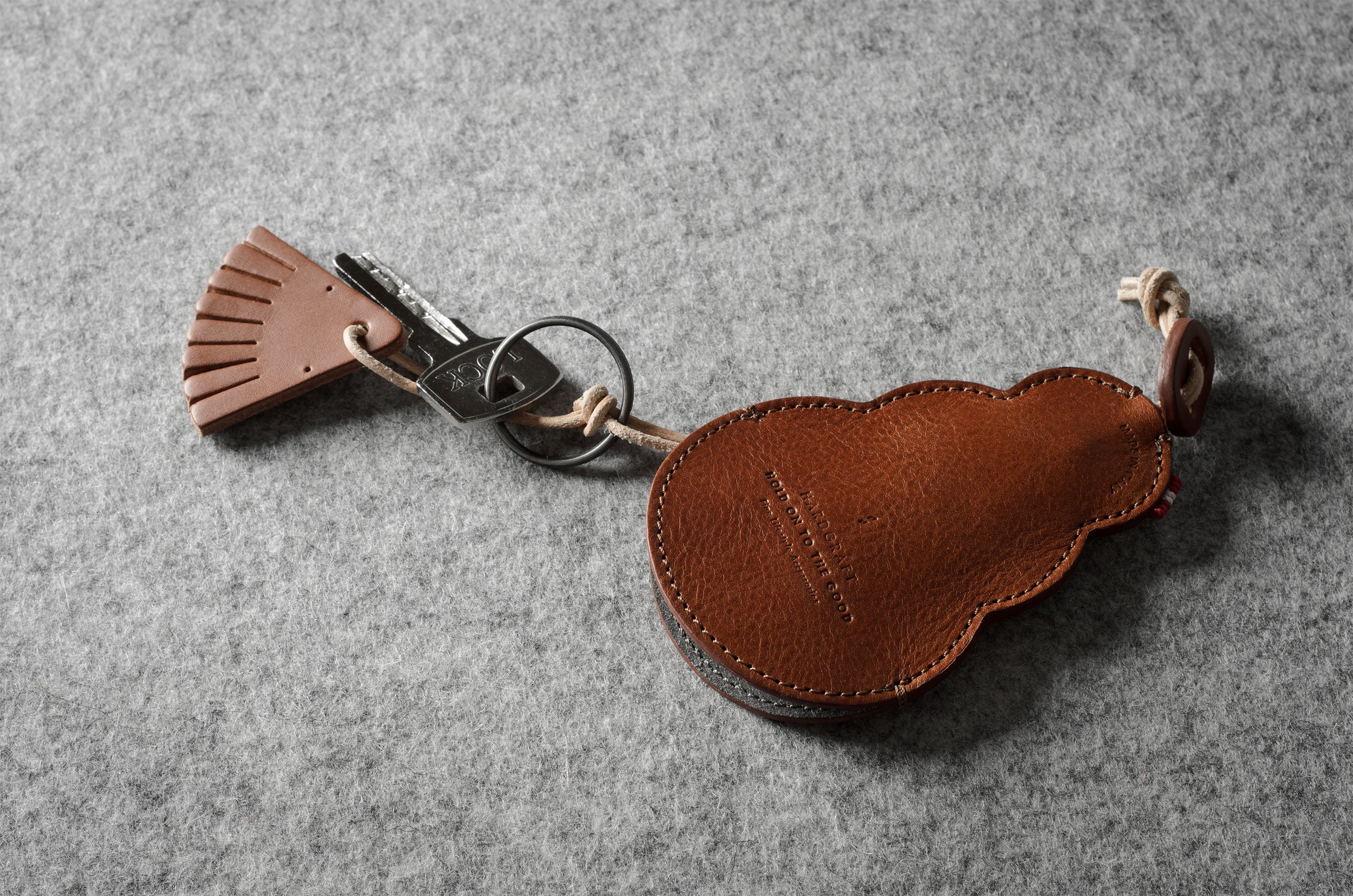 Brown leather keypouch with a leather string on a gray background
