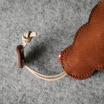Brown leather keypouch with a leather string on a gray background.