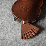 Brown leather keypouch with a leather string on a gray background
