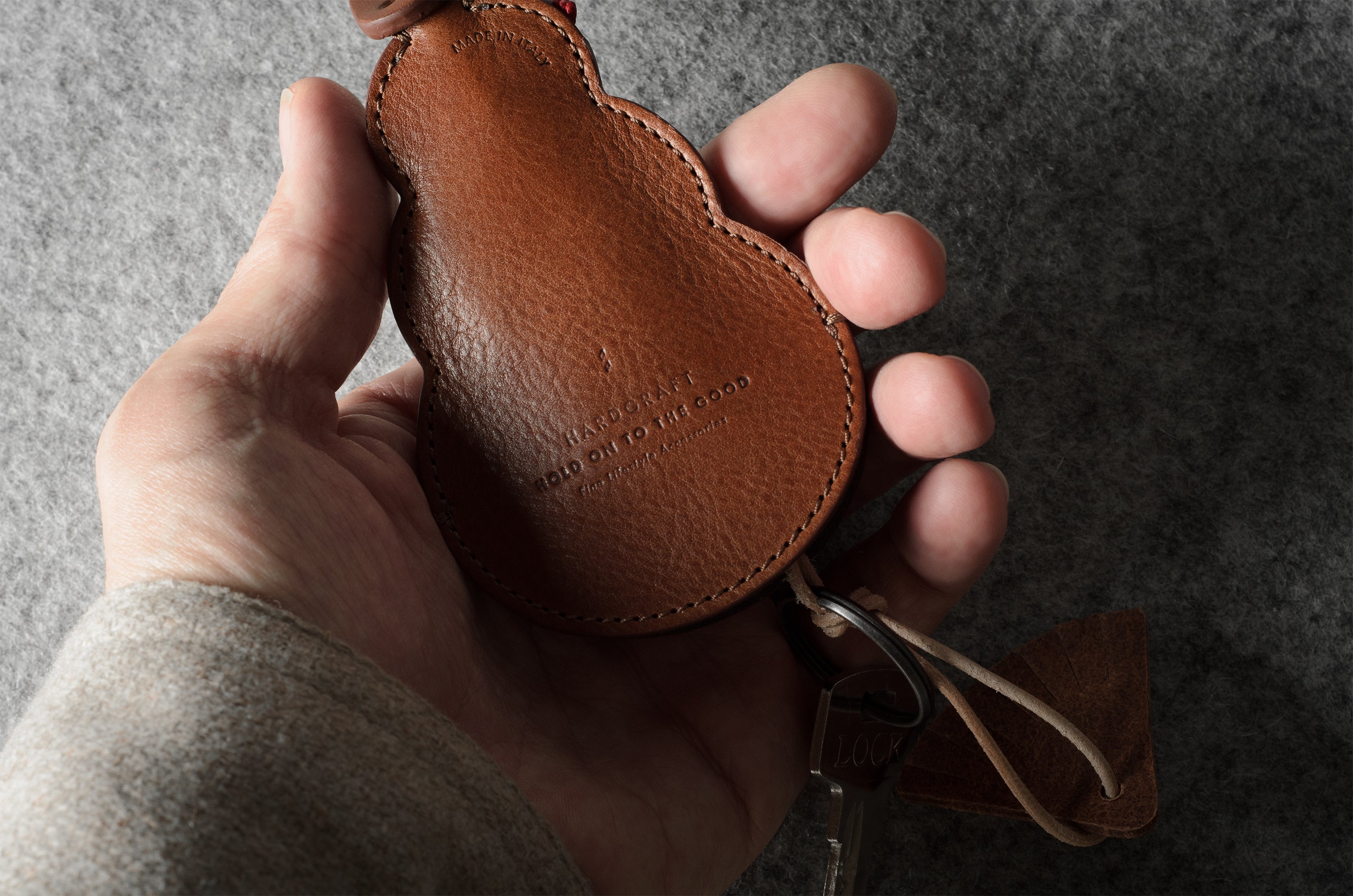 Brown leather keypouch with a leather string on a gray background
