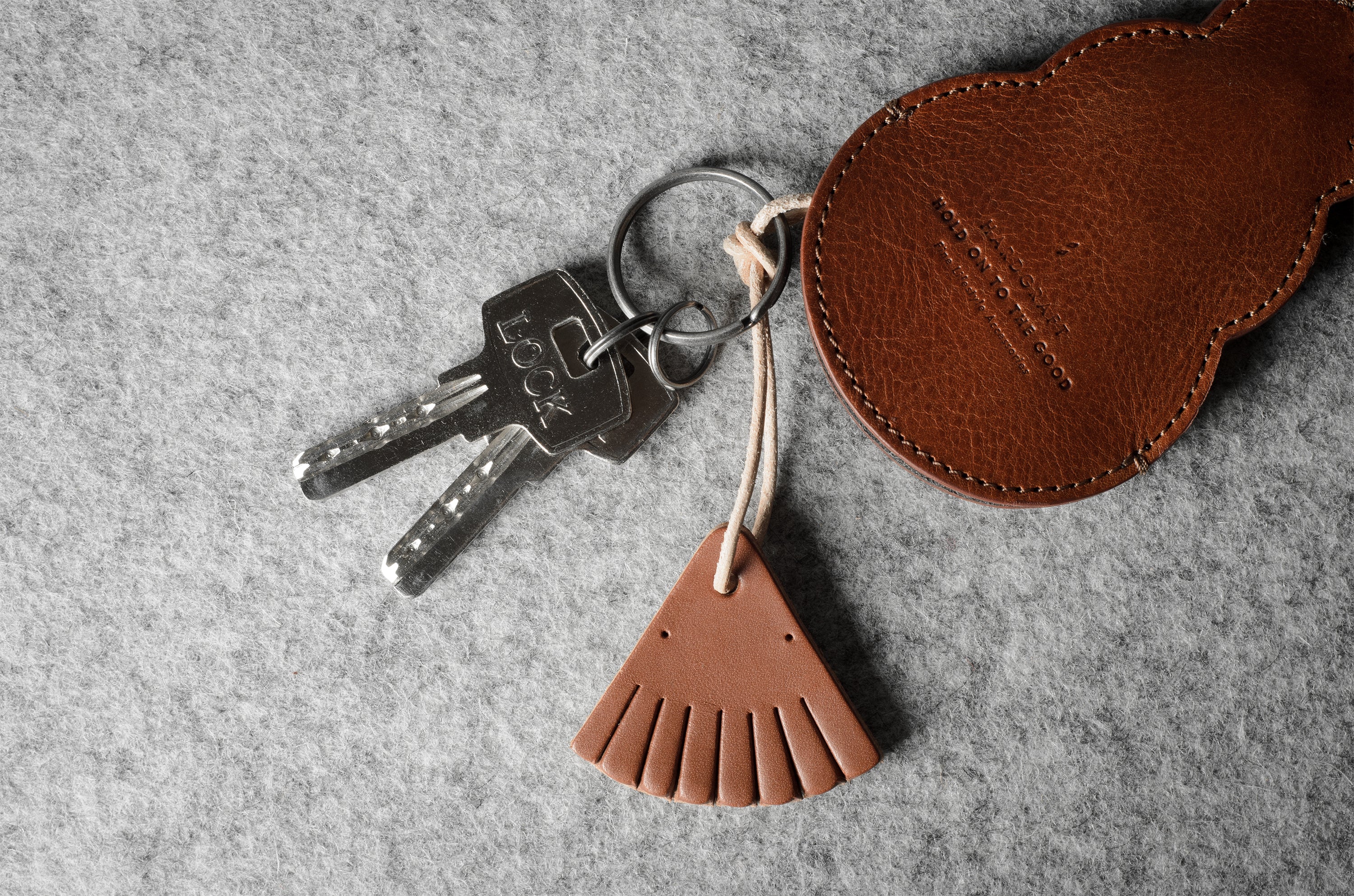 Brown leather keypouch with a leather string on a gray background