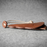 Brown leather keypouch with a leather string on a gray background