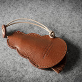 Brown leather keypouch with a leather string on a gray background