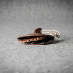 Brown leather keypouch with a leather string on a gray background