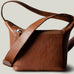 A classic brown leather camera bag with a shoulder strap and a zipper closure, viewed from the side.