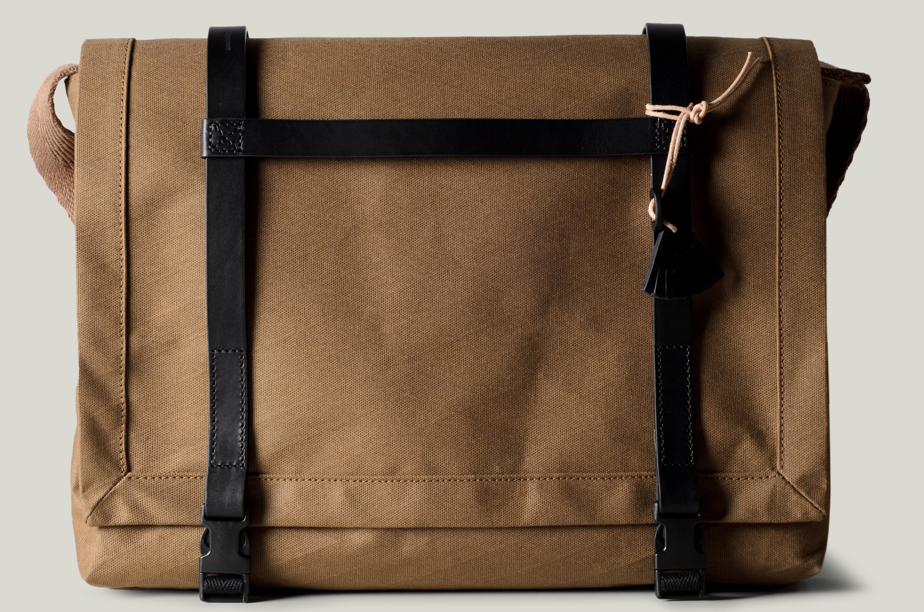 Brown technical fabric messenger bag with black leather straps.