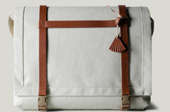 Light beige technical fabric messenger bag with brown leather straps.