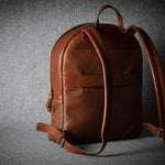 Brown leather backpack on a dark gray background