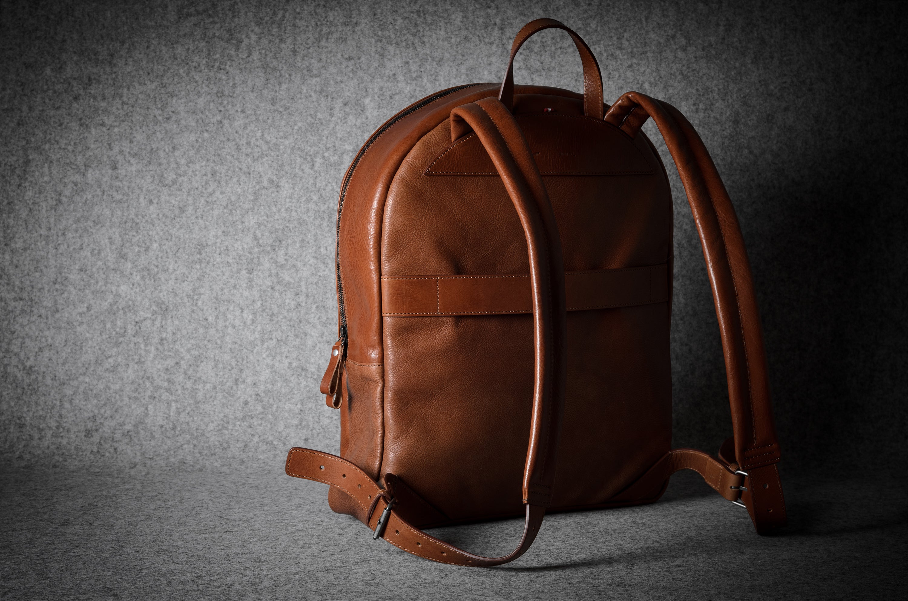 Brown leather backpack on a dark gray background