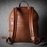 Brown leather backpack on a textured gray background