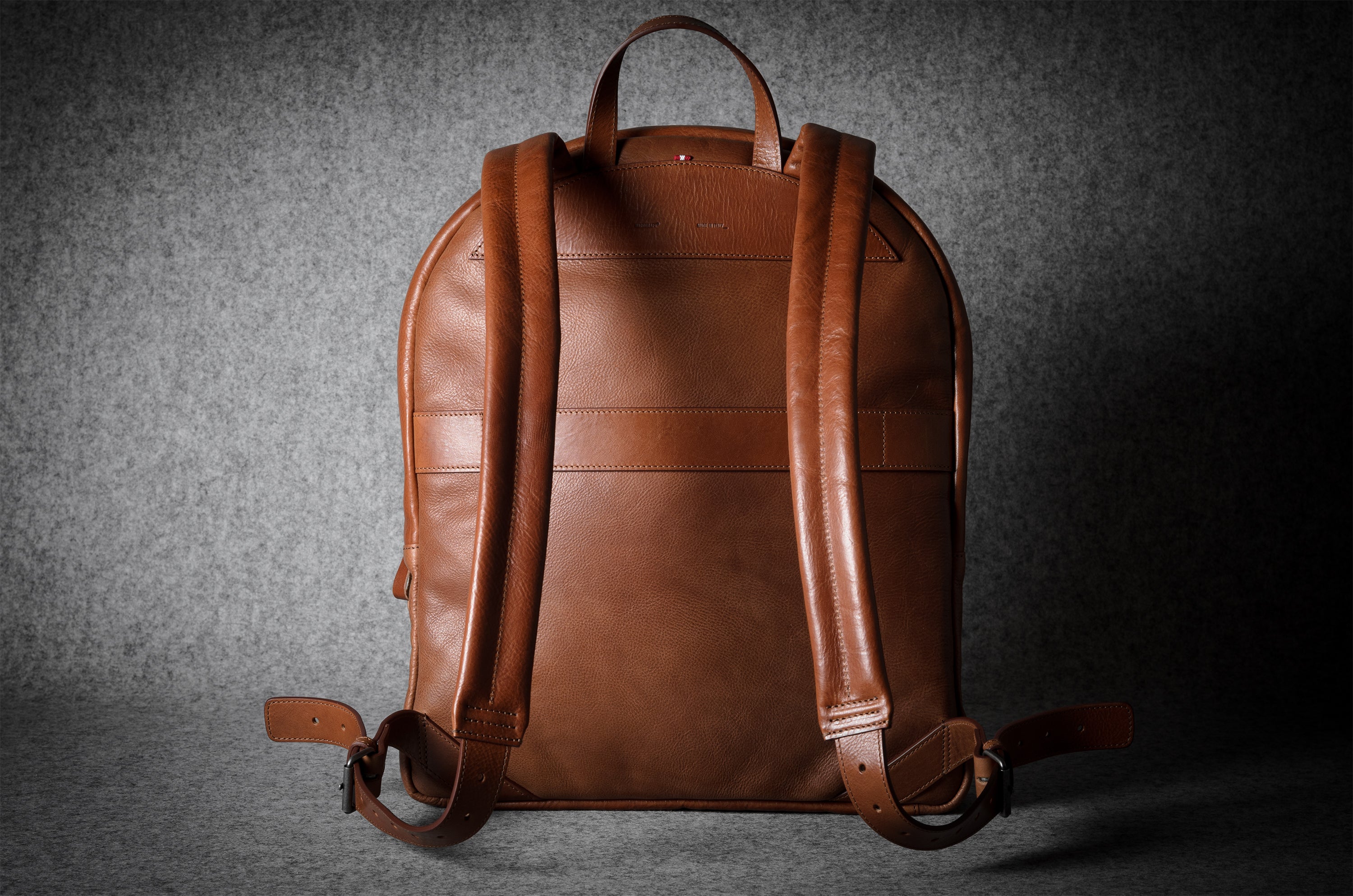 Brown leather backpack on a textured gray background