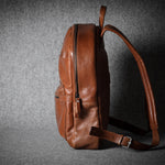 Brown leather backpack on a dark textured background