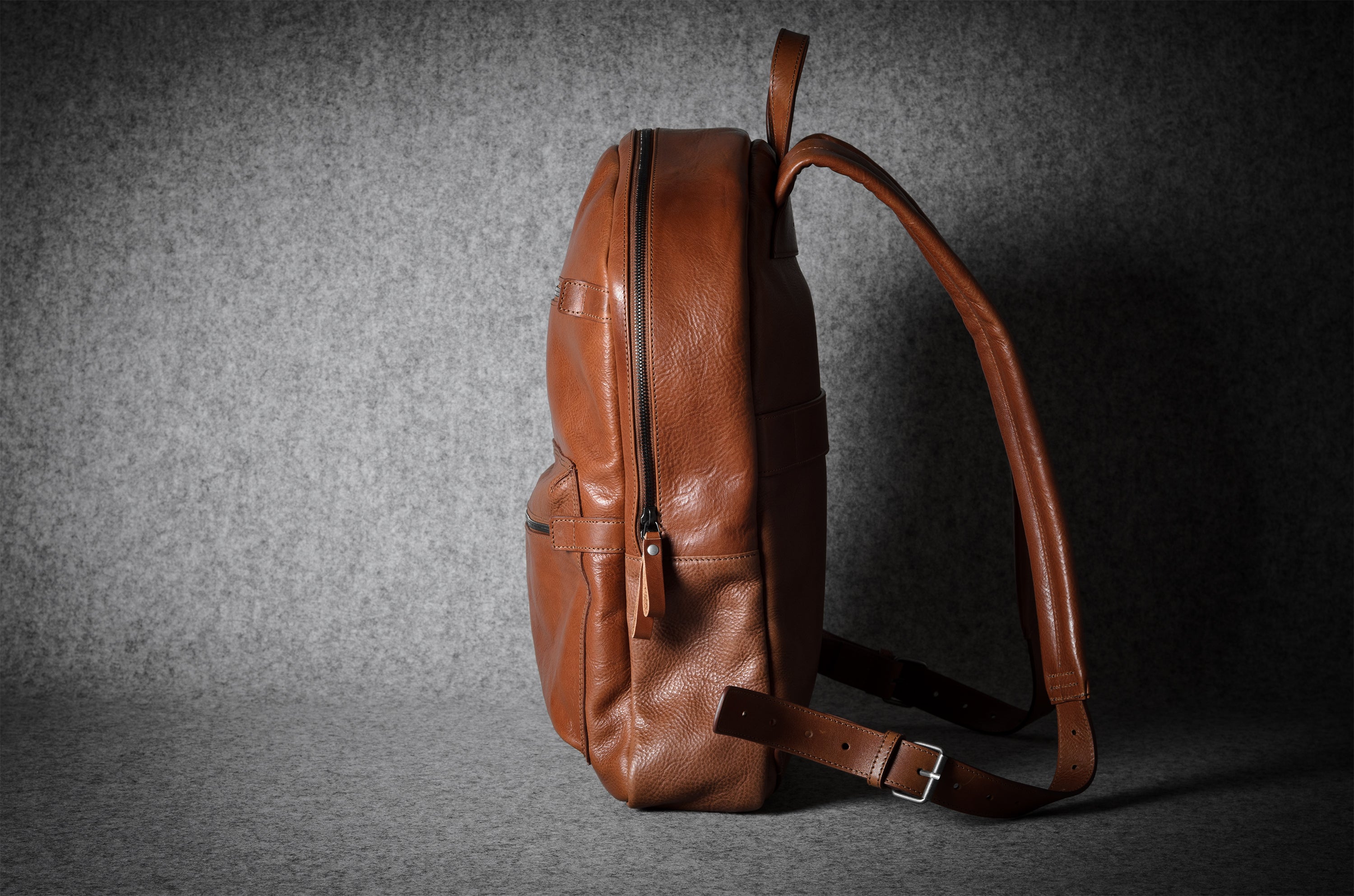 Brown leather backpack on a dark textured background