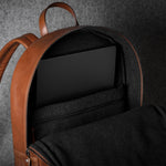 Brown leather backpack interior with straps on a dark gray background