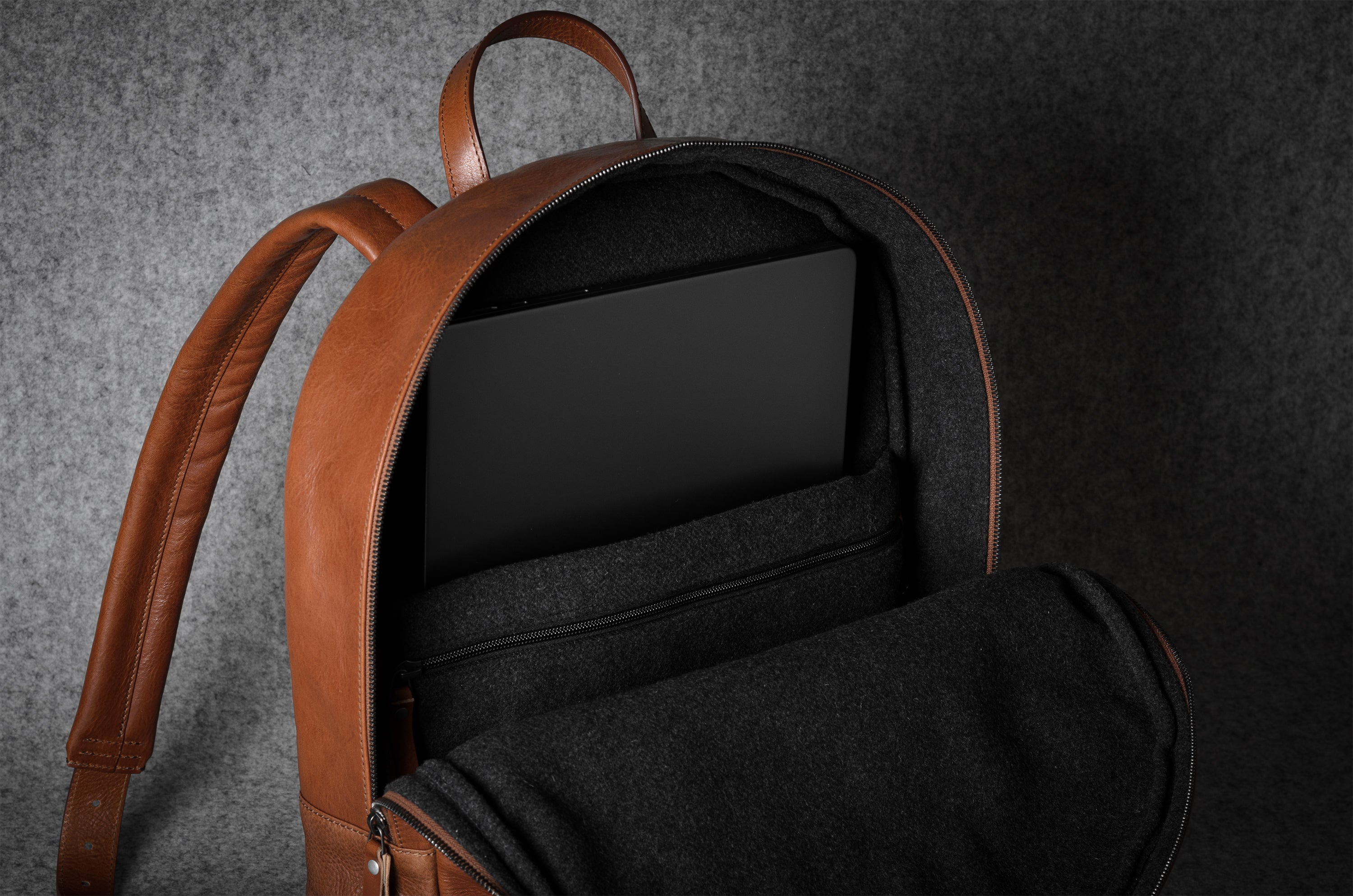 Brown leather backpack interior with straps on a dark gray background