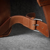 Close-up of a brown leather strap with a buckle on a dark background