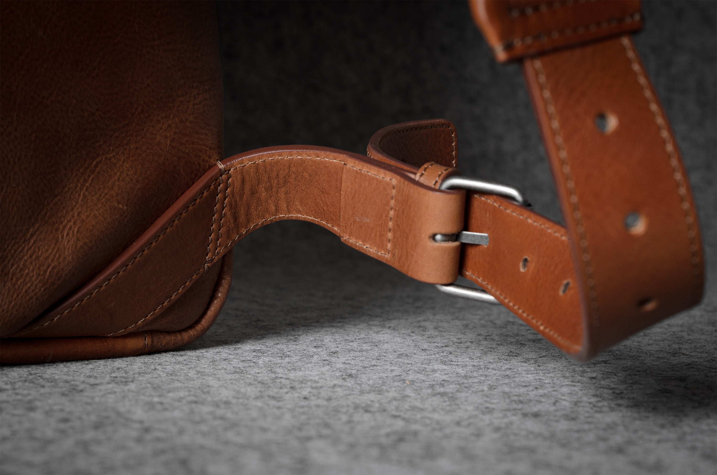 Close-up of a brown leather strap with a buckle on a dark background