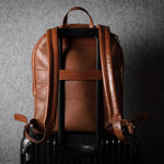 Brown leather backpack on a dark textured background
