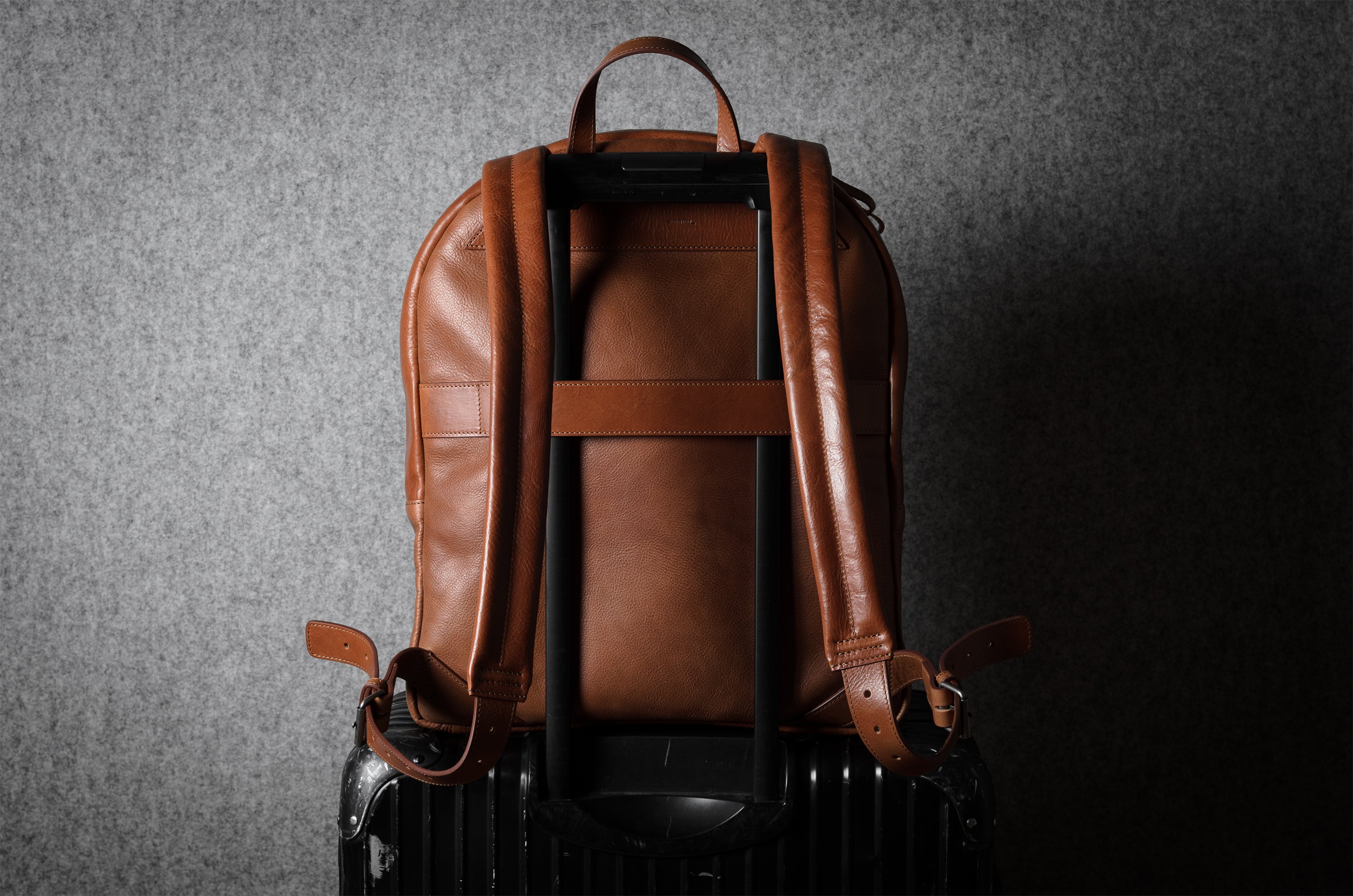 Brown leather backpack on a dark textured background