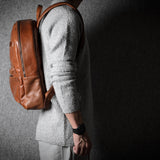 Person wearing a brown leather backpack against a dark background