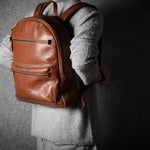 Person wearing a brown leather backpack against a dark background