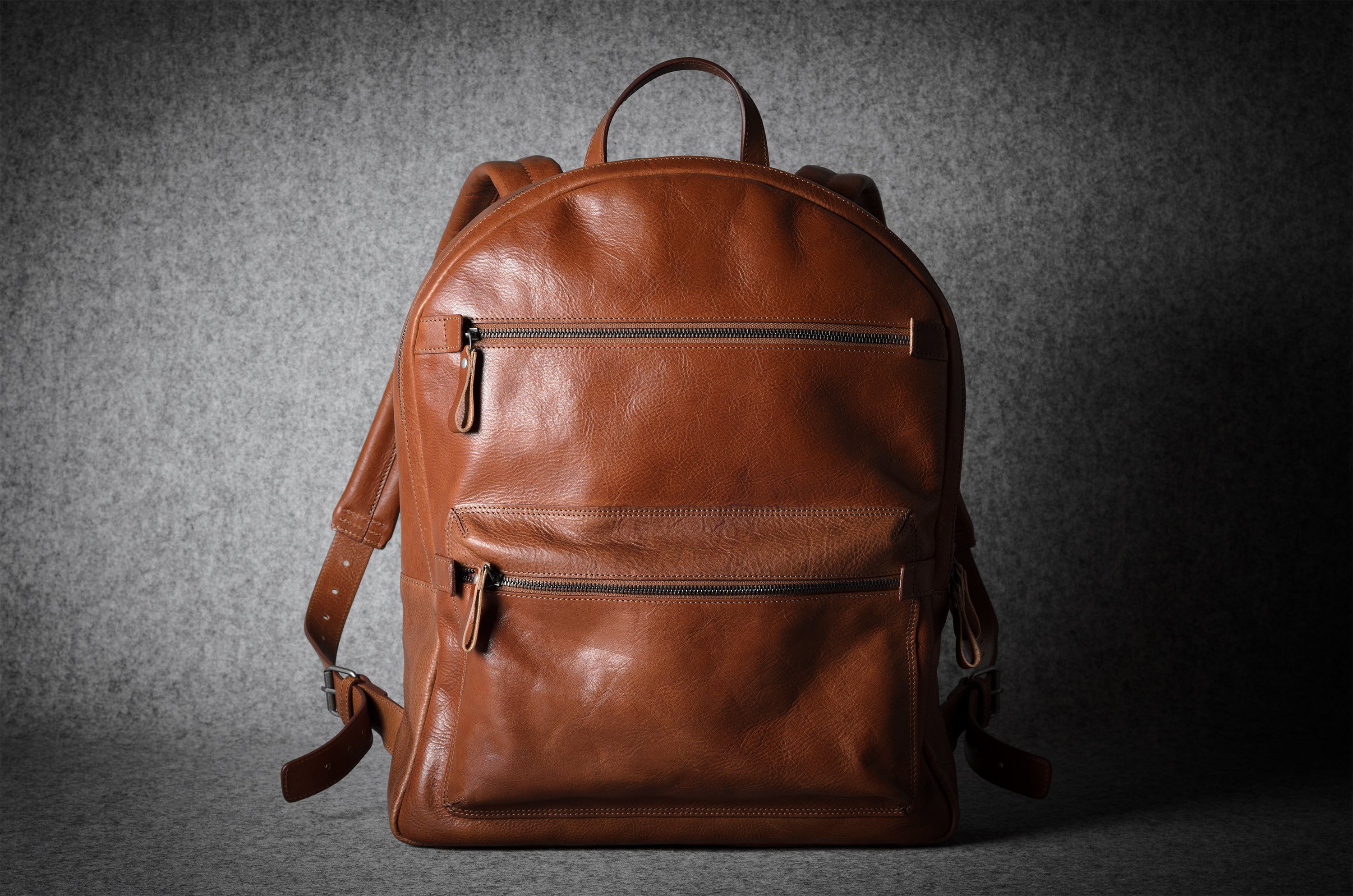 Brown leather backpack on a dark gray background