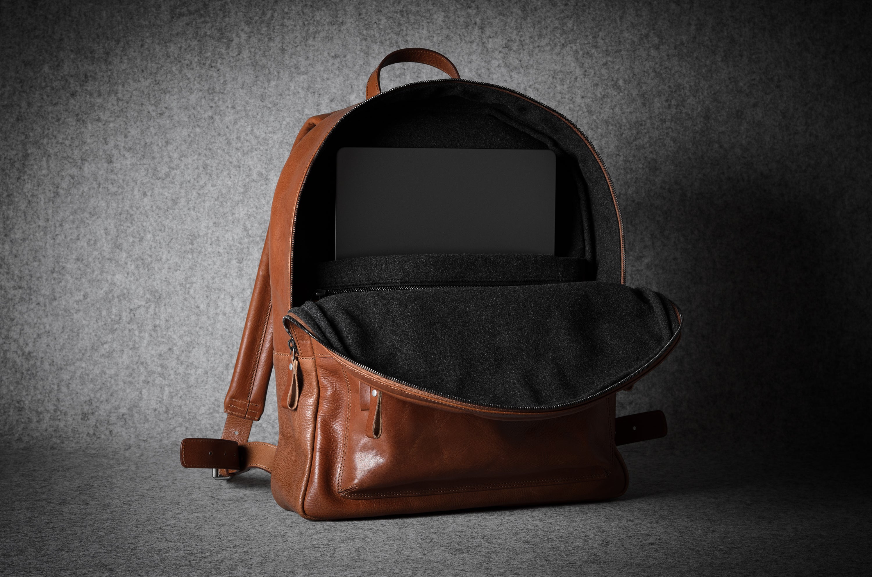 Brown leather backpack on a dark gray background
