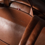 Close-up of a brown leather backpack with visible stitching