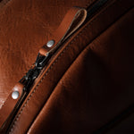 Close-up of a brown leather bag with a zipper