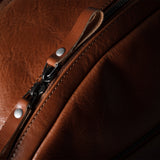 Close-up of a brown leather bag with a zipper