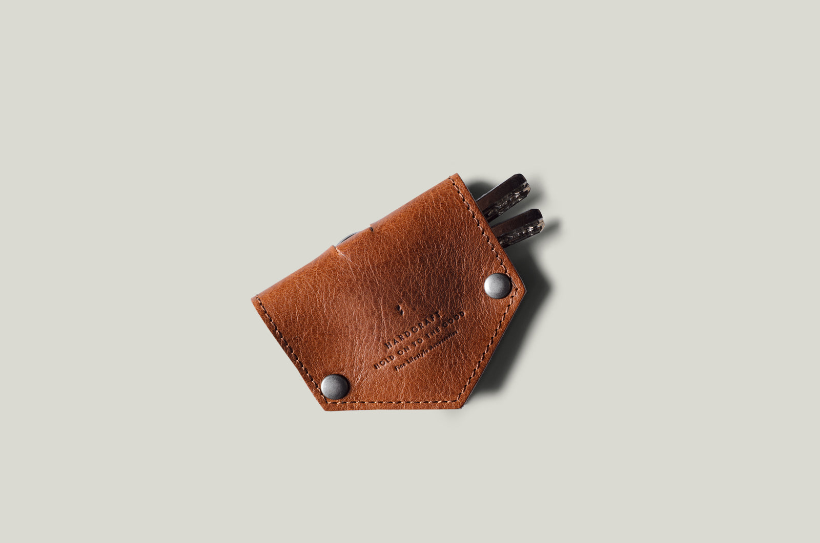 Brown leather key holder with keys on a light gray background