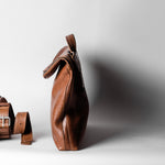 Brown leather bag and belt on a light gray background