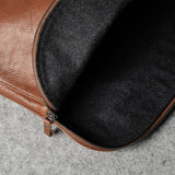 Brown leather bag with a dark grey interior on a gray surface