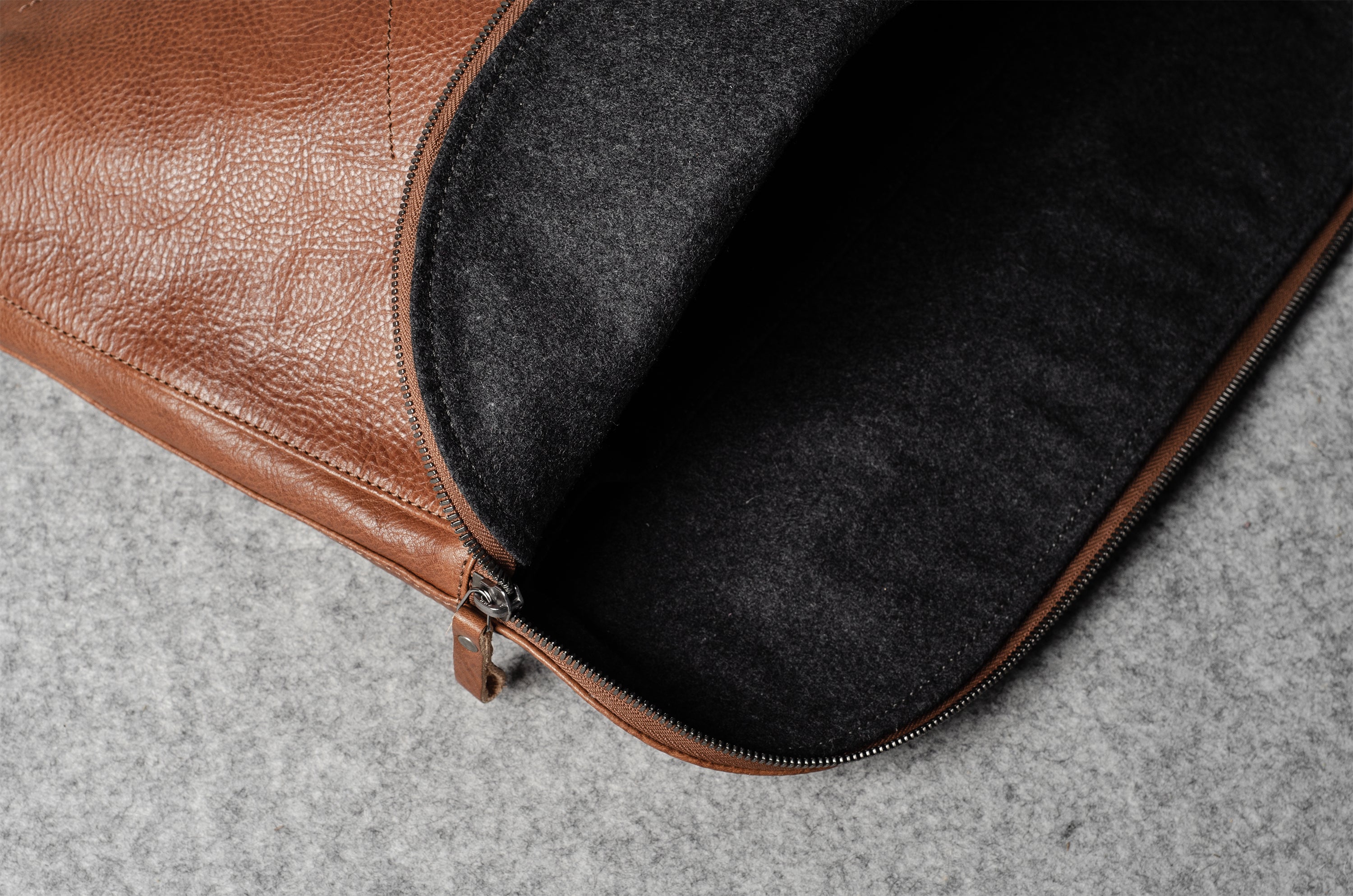 Brown leather bag with a dark grey interior on a gray surface