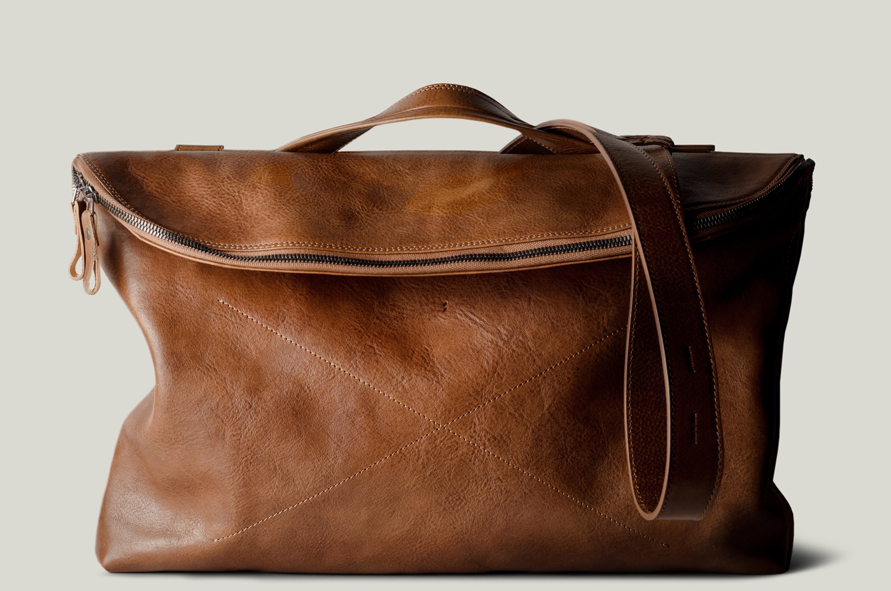 Brown leather shoulder bag with zip opening on white background